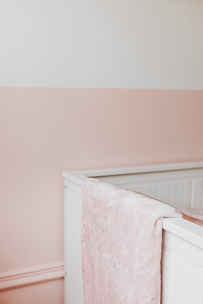 Minimalist nursery with a pink and white theme featuring a cozy crib.