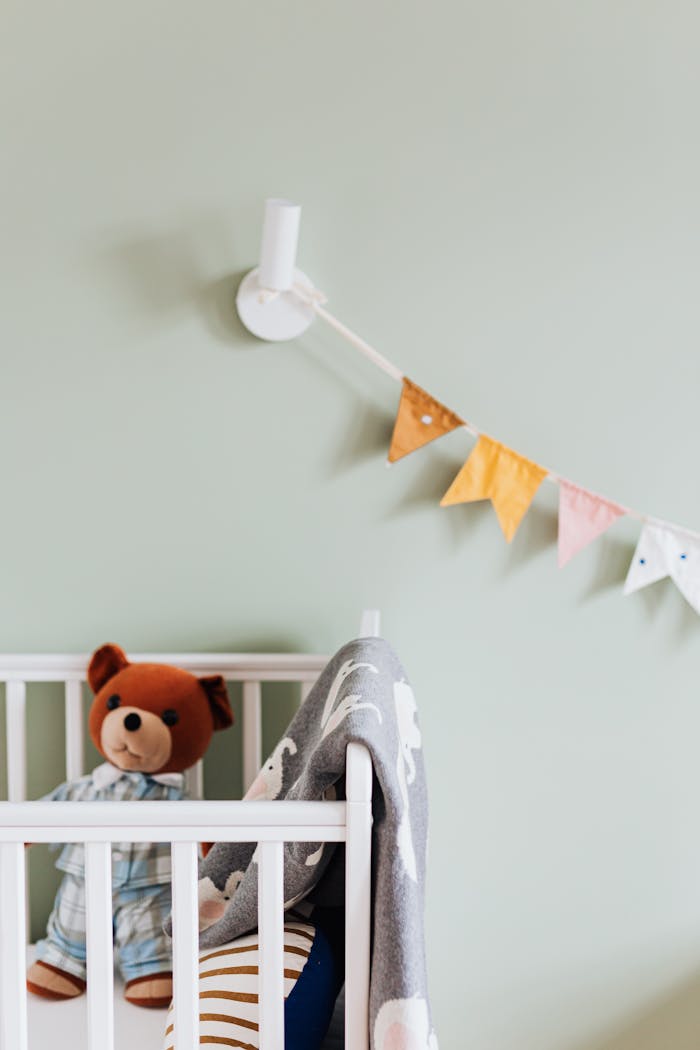 Charming baby nursery featuring a plush teddy bear, soft blankets, and vibrant bunting decor.