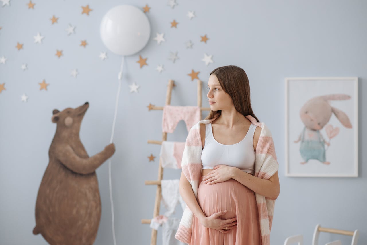 A beautiful pregnant woman in a stylish baby room, holding her belly.